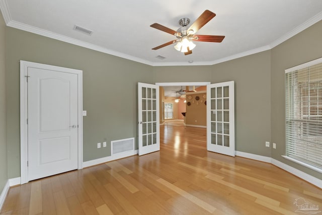 empty room featuring ceiling fan, ornamental molding, wood-type flooring, and french doors