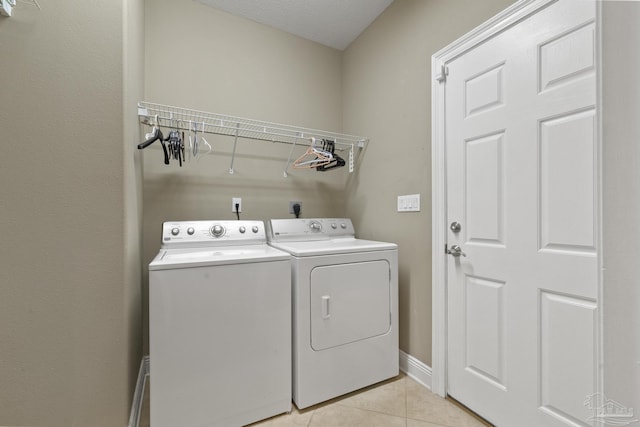 clothes washing area featuring light tile patterned floors and washer and clothes dryer