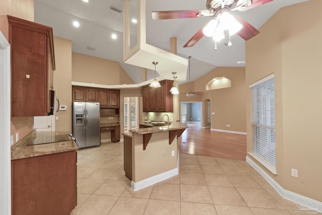 kitchen with light stone countertops, a breakfast bar, light tile patterned floors, and stainless steel fridge with ice dispenser