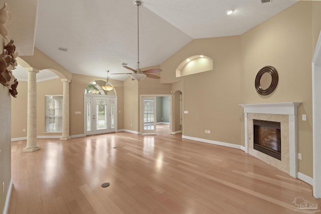 unfurnished living room featuring ornate columns, ceiling fan, a fireplace, vaulted ceiling, and light hardwood / wood-style flooring