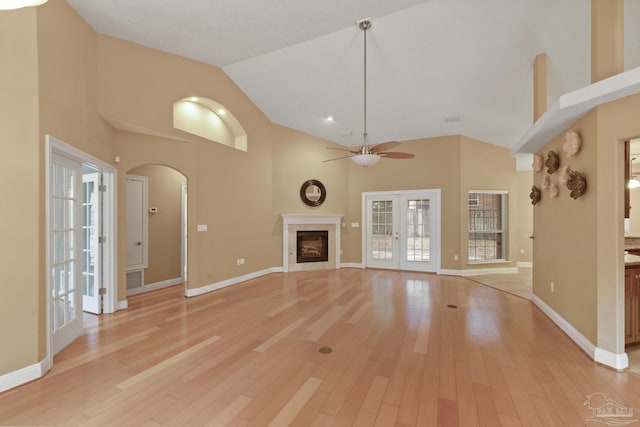 unfurnished living room featuring ceiling fan, french doors, light wood-type flooring, and high vaulted ceiling