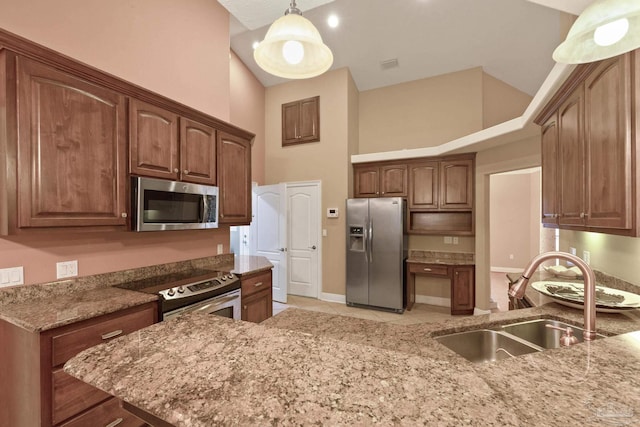 kitchen featuring sink, pendant lighting, stainless steel appliances, and a towering ceiling