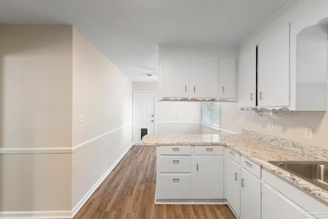 3481 Summit Blvd, Pensacola, FL 32503 - kitchen with wood finished floors, white cabinetry, light countertops, a peninsula, and baseboards