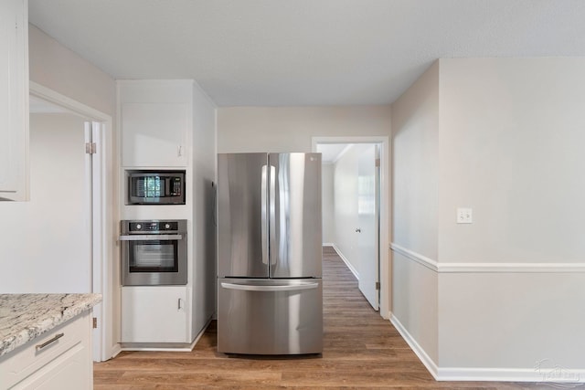 3481 Summit Blvd, Pensacola, FL 32503 - kitchen featuring stainless steel appliances, light wood-style flooring, white cabinets, light stone counters, and baseboards