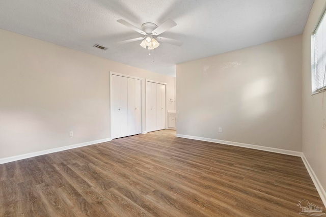 3481 Summit Blvd, Pensacola, FL 32503 - unfurnished bedroom featuring wood finished floors, multiple closets, baseboards, ceiling fan, and a textured ceiling
