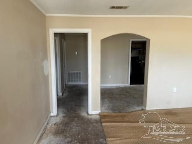 empty room with crown molding, arched walkways, visible vents, and baseboards