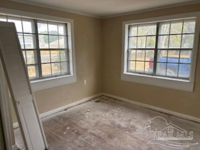 empty room featuring crown molding, plenty of natural light, and baseboards