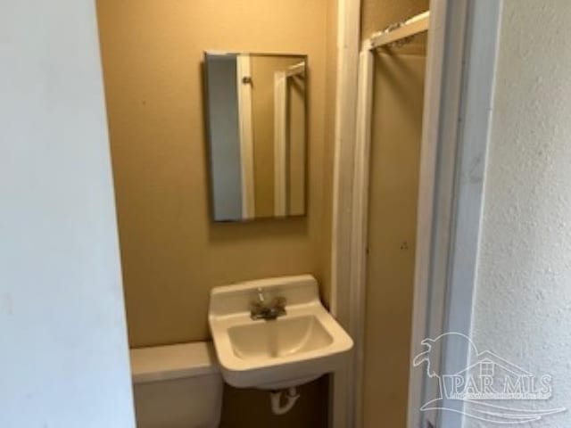 bathroom with walk in shower, toilet, and a sink