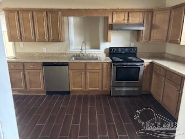 kitchen featuring a sink, appliances with stainless steel finishes, light countertops, under cabinet range hood, and dark wood-style flooring