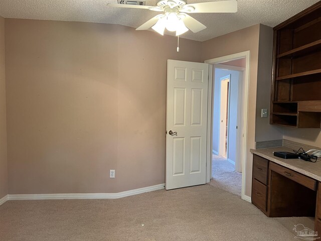 unfurnished office with a textured ceiling, ceiling fan, light carpet, and baseboards