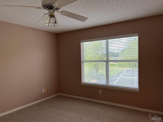 empty room featuring baseboards, ceiling fan, light carpet, and a textured ceiling