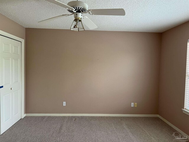 carpeted spare room with baseboards, a ceiling fan, and a textured ceiling
