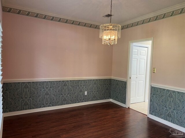 empty room featuring wainscoting, wood finished floors, a notable chandelier, and wallpapered walls