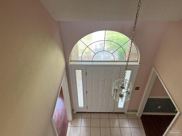entryway with baseboards, a textured ceiling, and light tile patterned floors