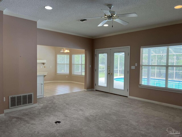 unfurnished living room featuring french doors, a textured ceiling, light colored carpet, crown molding, and visible vents