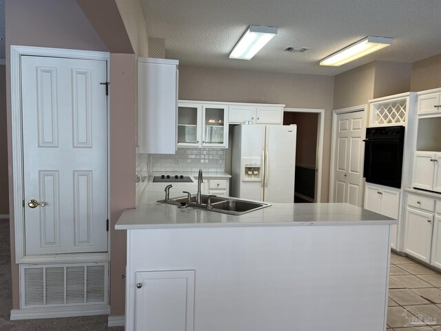 kitchen with visible vents, a sink, black appliances, and glass insert cabinets