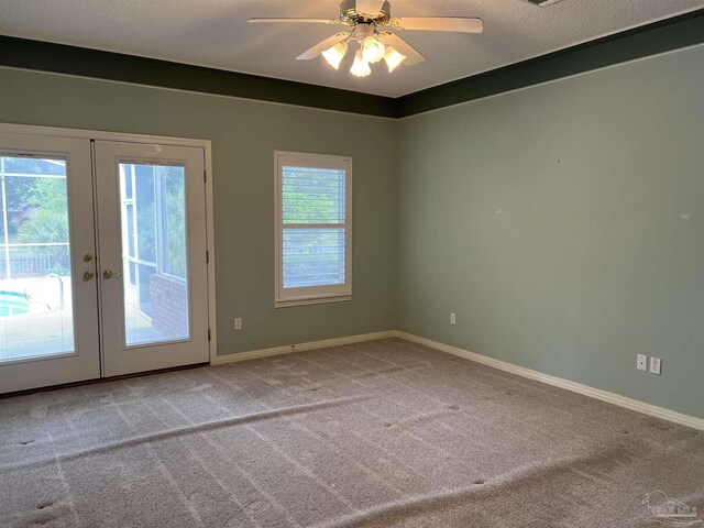 carpeted spare room featuring a ceiling fan, baseboards, and french doors