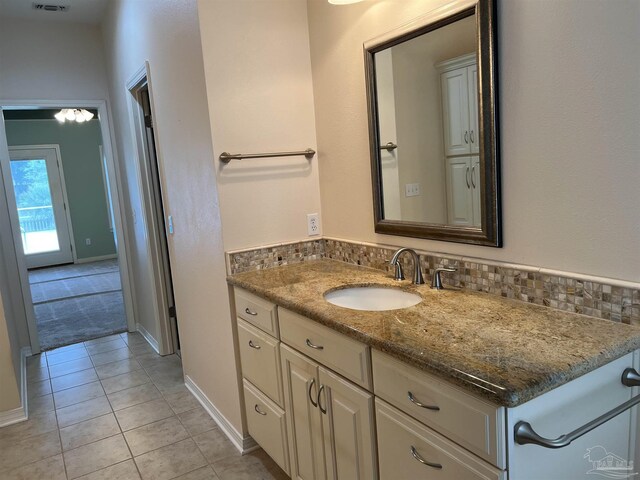 bathroom with vanity, tile patterned flooring, baseboards, and backsplash