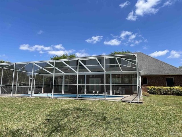 rear view of house with brick siding, an outdoor pool, and a yard