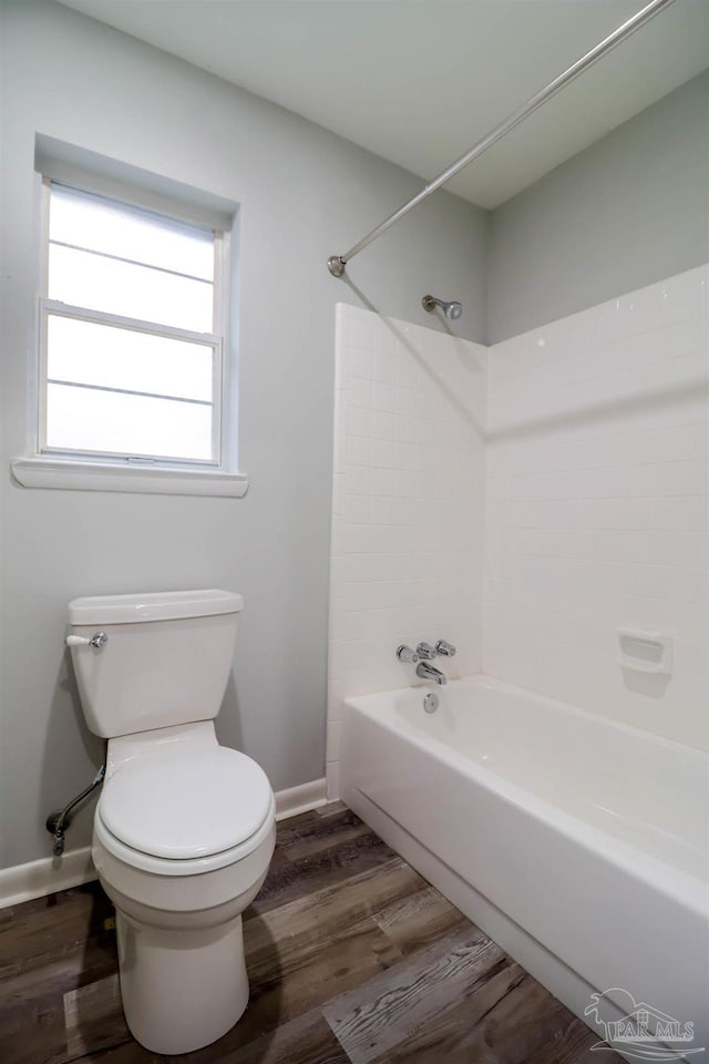 bathroom featuring hardwood / wood-style flooring, toilet, and washtub / shower combination