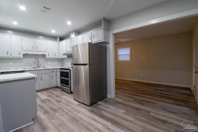 kitchen featuring appliances with stainless steel finishes, sink, light hardwood / wood-style flooring, and white cabinets