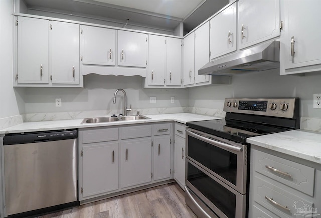 kitchen featuring stainless steel appliances, sink, white cabinets, and light wood-type flooring