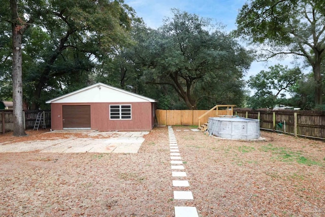 view of yard featuring a garage, an outdoor structure, and a fenced in pool