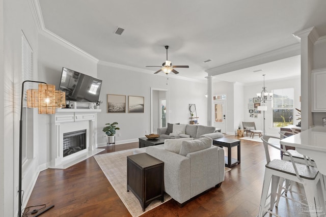 living room with ceiling fan with notable chandelier, dark wood-type flooring, and crown molding