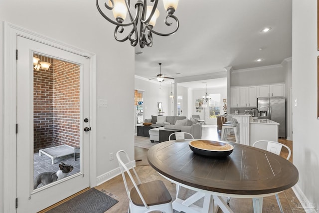 dining room featuring sink, light hardwood / wood-style floors, ceiling fan with notable chandelier, and ornamental molding