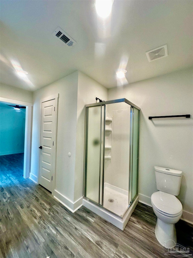 bathroom with hardwood / wood-style floors, toilet, and a shower with shower door