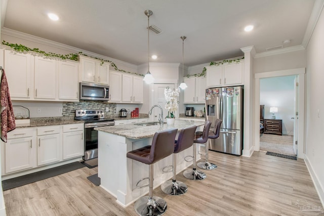 kitchen with a sink, white cabinetry, stainless steel appliances, and light wood-style floors