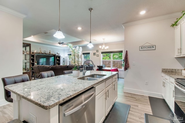 kitchen featuring crown molding, a sink, appliances with stainless steel finishes, baseboards, and open floor plan