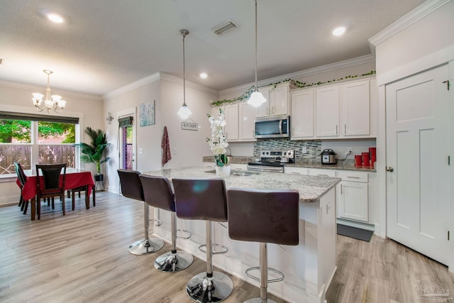 kitchen featuring white cabinetry, light wood-style flooring, appliances with stainless steel finishes, visible vents, and a notable chandelier