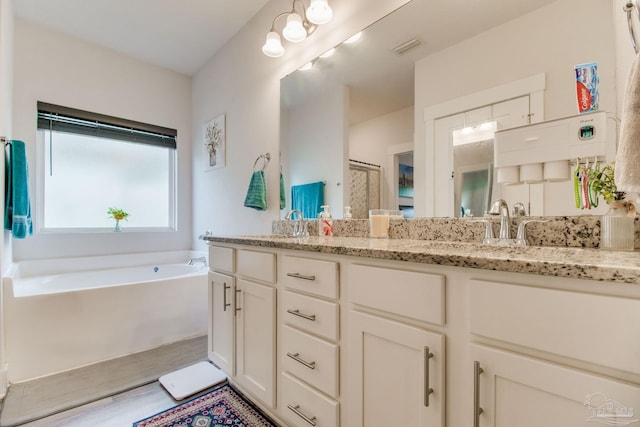 bathroom featuring a garden tub, a sink, double vanity, and visible vents