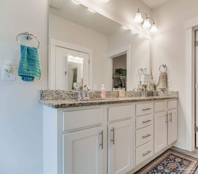bathroom with double vanity, a sink, visible vents, and a spacious closet