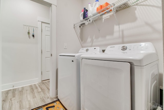 clothes washing area featuring light wood-style floors, baseboards, laundry area, and washing machine and dryer