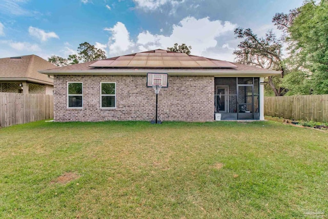 back of property featuring a lawn, solar panels, and a sunroom