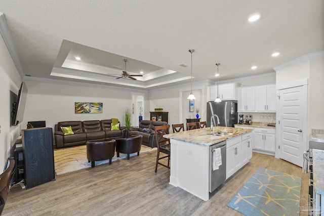 kitchen featuring stainless steel appliances, white cabinetry, a kitchen island with sink, and a tray ceiling