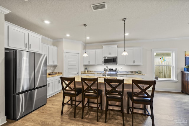 kitchen featuring white cabinetry, an island with sink, sink, hanging light fixtures, and stainless steel appliances