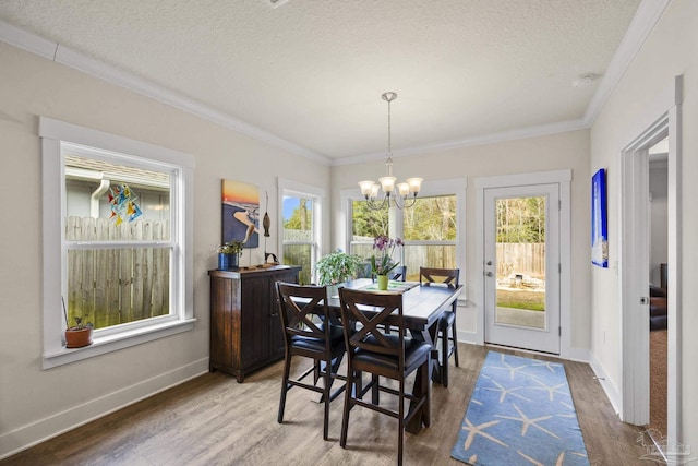 dining room featuring hardwood / wood-style floors, crown molding, a textured ceiling, and a chandelier