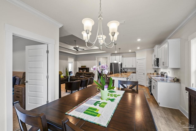 dining area with ceiling fan with notable chandelier, ornamental molding, and dark hardwood / wood-style floors