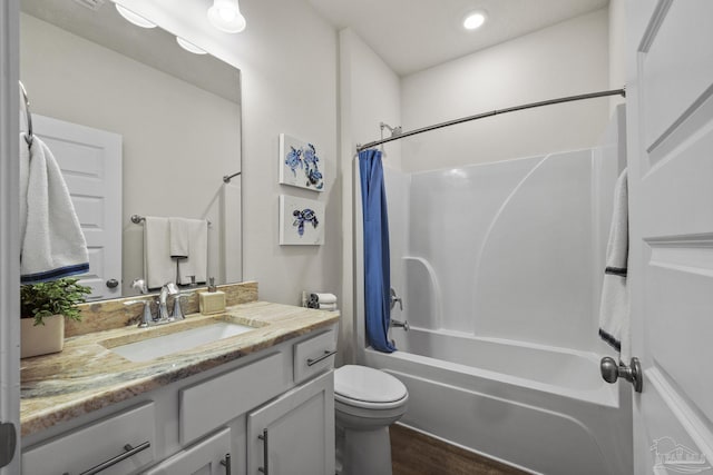 full bathroom featuring hardwood / wood-style flooring, vanity, shower / bath combination with curtain, and toilet