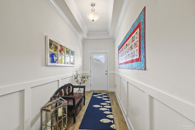 doorway to outside featuring crown molding, a raised ceiling, and hardwood / wood-style flooring