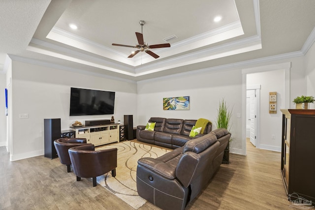 living room with crown molding, a tray ceiling, light hardwood / wood-style floors, and ceiling fan