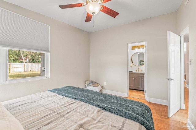 bedroom featuring sink, ensuite bathroom, ceiling fan, and light wood-type flooring