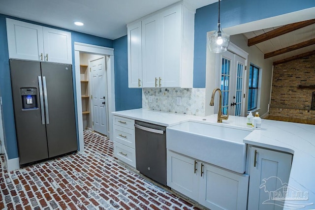 kitchen featuring white cabinetry, stainless steel appliances, vaulted ceiling with beams, and sink