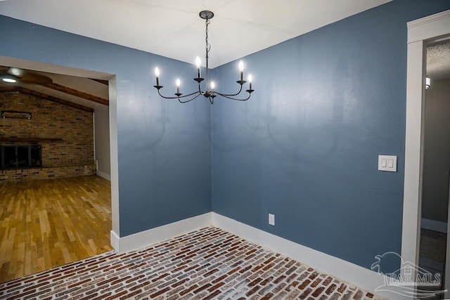 unfurnished dining area featuring a fireplace, wood-type flooring, lofted ceiling, and a notable chandelier