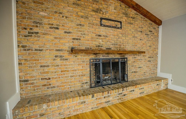 room details with beam ceiling, wood-type flooring, and a fireplace