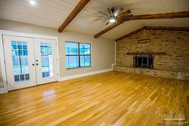 unfurnished living room featuring lofted ceiling with beams, french doors, light hardwood / wood-style floors, ceiling fan, and brick wall