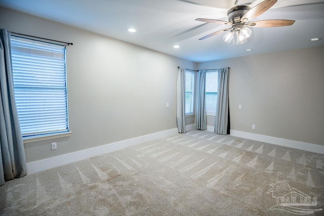 spare room with a wealth of natural light, light carpet, and ceiling fan